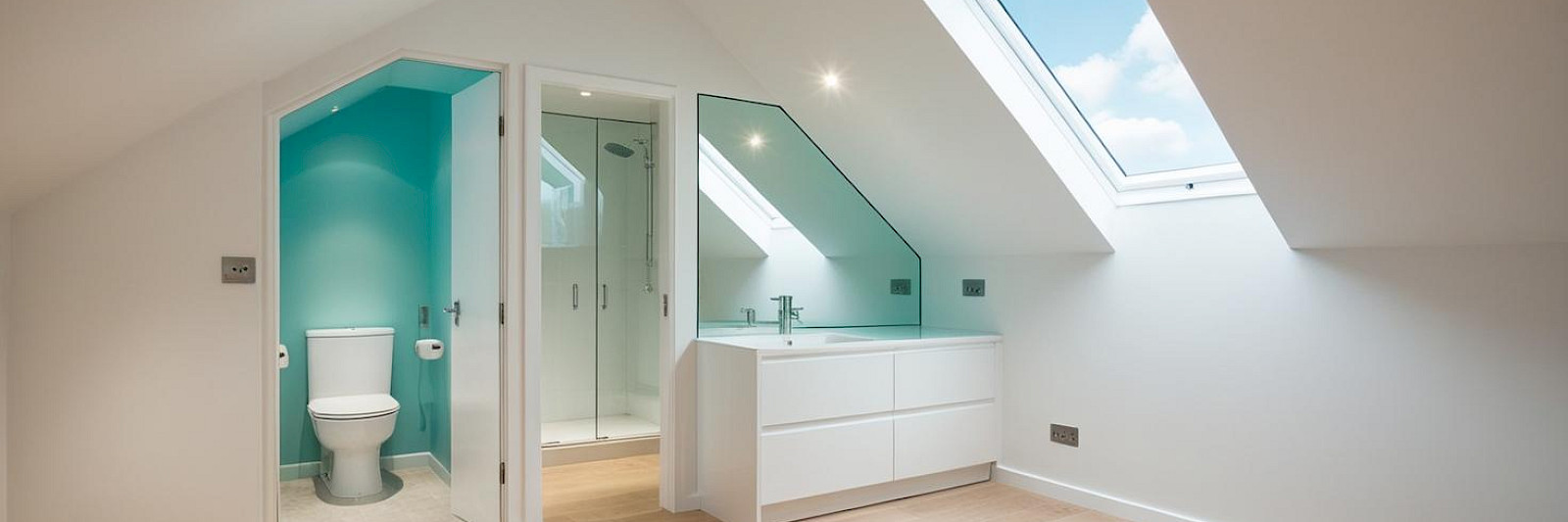 Stunning loft conversion bedroom featuring a modern en-suite bathroom, flooded with natural light. The airy space is accented with a hint of turquoise, creating a serene and stylish retreat. Perfect for a contemporary home makeover.