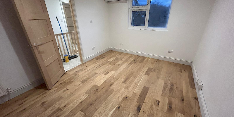 Loft conversion bedroom finished with white walls and wooden floor.