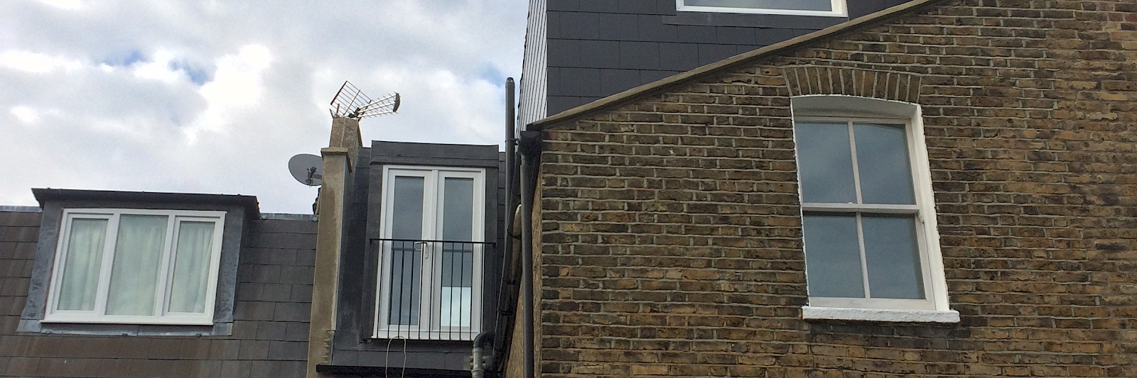 Elegant L-shaped loft conversion featuring a French balcony that enhances the space with natural light and a touch of luxury.