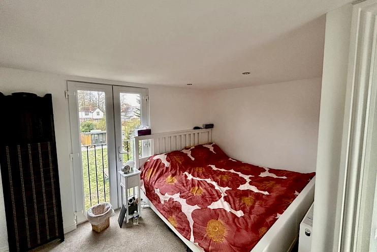 Stylish loft conversion bedroom with a French balcony, offering a perfect blend of comfort and elegance.