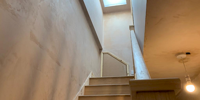 Bright, raw plaster hallway leading to a loft with a skylight, flooding the space with natural light. Perfect for loft conversion ideas and hallway inspiration.